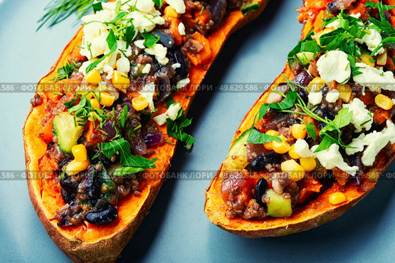 Sweet potato stuffed with vegetables and cottage cheese and baked in halves. Diet food, roast yam. Sweet potato stuffed with vegetables and cottage cheese. Стоковое фото, агентство Ingram Publishing / Фотобанк Лори