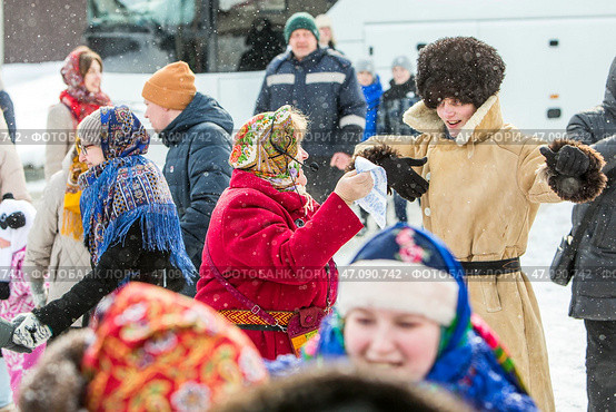 Танцующие женщина с платком и молодой парень в тулупе и папахе. Празднование Масленицы на территории Кафедрального собора в честь Преображения Господня. Бердск, Новосибирская область, Западная Сибирь, Россия. Редакционное фото, фотограф Евгений Мухортов / Фотобанк Лори