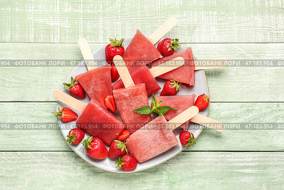Тарелка с морожеными на палочке со вкусом клубники на зеленом деревянном фоне. Стоковое фото, фотограф Pixel_shot / Фотобанк Лори