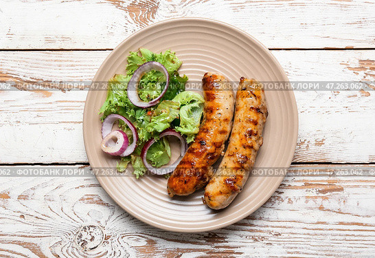 Тарелка с вкусными колбасками-гриль на деревянном столе. Стоковое фото, фотограф Pixel_shot / Фотобанк Лори