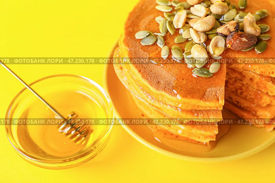 Тарелка с вкусными тыквенными оладьями и медом на цветном фоне. Стоковое фото, фотограф Pixel_shot / Фотобанк Лори