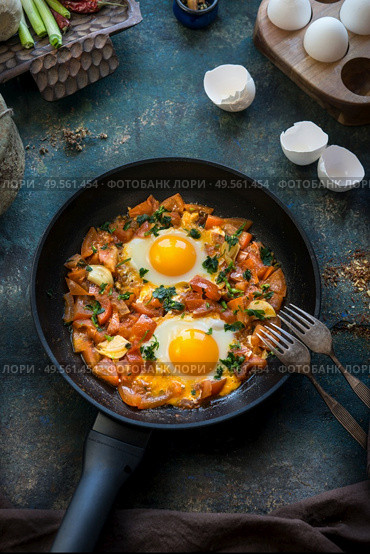 Tasty fried egg with tomatoes paprika sauce in fried pan with forks. Healthy breakfast. Shakshuka original on rustic background . Top view. Стоковое фото, агентство Ingram Publishing / Фотобанк Лори