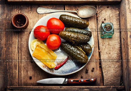 Tasty pickles on a plate. Pickled cucumbers, tomatoes and peppers. Rustic, top view. Cold appetizer, pickled vegetables. Стоковое фото, агентство Ingram Publishing / Фотобанк Лори