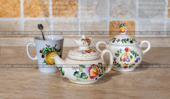 Tea party preparation. Beautiful: teapot, sugar bowl and cup with spoon on the kitchen table. Handmade items. Selective focus. Стоковое фото, фотограф Анищенко Геннадий / Фотобанк Лори