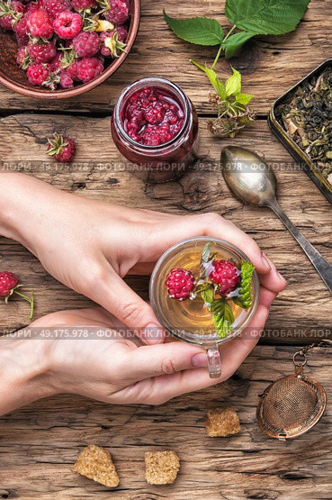 Tea with raspberries. Tea cup with raspberry warming tea in hands. Стоковое фото, агентство Ingram Publishing / Фотобанк Лори