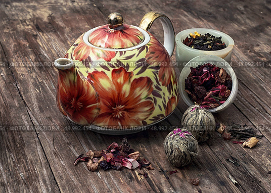 teapot and scattered tea leaves on vintage wooden background. brewed leaf tea in glass jar. Стоковое фото, агентство Ingram Publishing / Фотобанк Лори