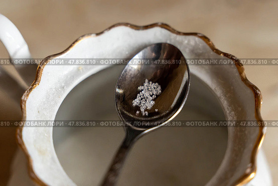 Teaspoon holding few crystals of sugar over empty sugar bowl. Стоковое фото, фотограф Андрей Знаменский / Фотобанк Лори
