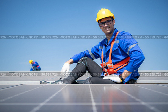 Technician repairing solar panels rest in the scorching sun on a factory roof covered with solar panels to receive solar energy. Стоковое фото, агентство Ingram Publishing / Фотобанк Лори