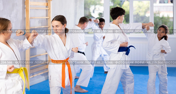 Teen girl karateka honing punches during kumite in training room. Стоковое фото, фотограф Яков Филимонов / Фотобанк Лори