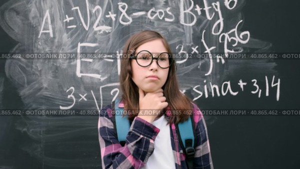 Teen girl little student in glasses and blue backpack standing and thinking on chalkboard background. Then she is pointing up with finger because finds the answer. Brainstorming and new idea concept. Стоковое видео, видеограф Марина Демидюк / Фотобанк Лори