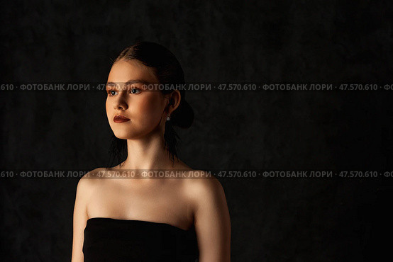 Teen Girl Poses Elegantly Against a Dark Backdrop Showcasing Her Beauty and Confidence. Стоковое фото, фотограф Aleksandr Golubev / Фотобанк Лори