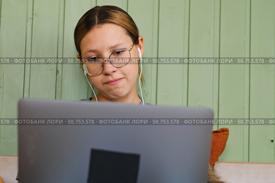 Teen girl school student wear headphones watching online webinar, talking through webcam looking at laptop. Teenager conducting video conference on computer at home, chatting online with friends. 4K. Стоковое фото, фотограф Марина Демидюк / Фотобанк Лори