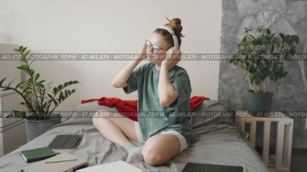Teen girl writing daily goals in notebook, creating to-do list for day. Organized space with planner, markers, student listening to music on headphones during break, conscious self-development. Стоковое видео, видеограф Енваев Андрей / Фотобанк Лори
