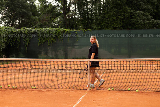 Teenage Girl Practices Her Tennis Skills on a Sunny Outdoor Court Surrounded by Nature. Стоковое фото, фотограф Aleksandr Golubev / Фотобанк Лори