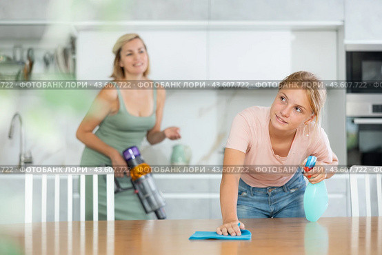 Teenage girl wiping table with rag and detergent at home kitchen. Стоковое фото, фотограф Яков Филимонов / Фотобанк Лори