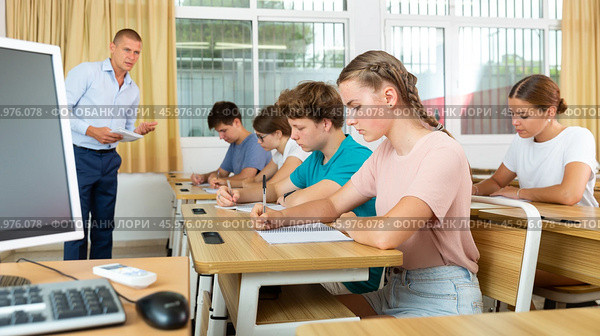 Teenage students studying in classroom with teacher, writing lectures. Стоковое фото, фотограф Яков Филимонов / Фотобанк Лори
