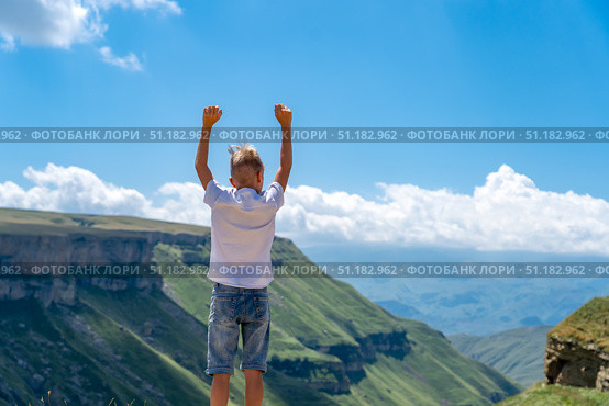 Teenager boy standing on top of mountain with raised hands, looking away with pleasure. School boy hiking in mountains, Мальчик стоит на краю пропасти подняв руки вверх, Тобот, Дагестан. Стоковое фото, фотограф Данила Большаков / Фотобанк Лори
