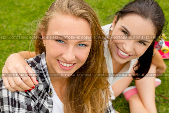Teens best friends sitting on the grass smiling and having a good time. Стоковое фото, агентство Ingram Publishing / Фотобанк Лори