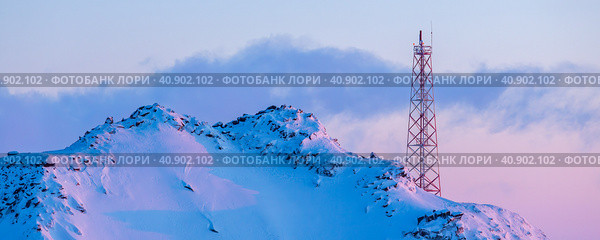 Телекоммуникационная вышка на склоне заснеженной горы. Зимний арктический пейзаж. Вид на вершину горы и металлическую башню с антеннами. Связь на Крайнем Севере в Арктике. Стоковое фото, фотограф Андрей Степанов / Фотобанк Лори