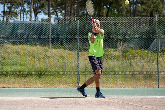 Tennis player hitting backhand at ball with racket on court. Стоковое фото, агентство Ingram Publishing / Фотобанк Лори