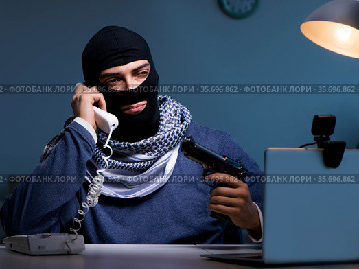 Terrorist burglar with gun working at computer. Стоковое фото, фотограф Elnur / Фотобанк Лори