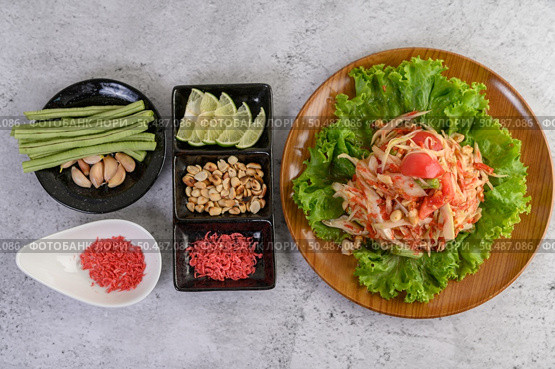 Thai papaya salad on salad in a wooden plate with Yardlong beans and garlic, Top view. Стоковое фото, агентство Ingram Publishing / Фотобанк Лори