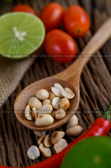 Thai style spicy food, Som Tum food concept, props decoration Garlic, lemon,  tomatoes, chili and peanuts on wood spoon on wood table. Стоковое фото, агентство Ingram Publishing / Фотобанк Лори