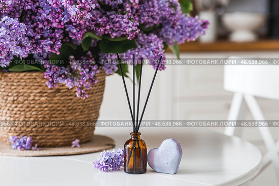 The aroma diffuser. Spring aromatic lilac perfumes for the home in a glass bottle with sticks as an air freshener in the house and soap. Aromatherapy, cozy atmosphere, comfort and relaxation. Стоковое фото, фотограф Photojuli / Фотобанк Лори