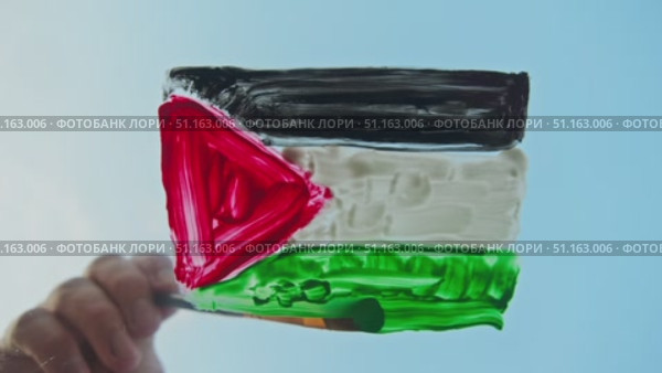 The artist paints the flag of Palestine in bright colors on glass against the background of a serene azure sky, embodying security and serenity. Стоковое видео, видеограф Strunov David / Фотобанк Лори
