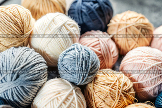The background is made of balls of wool yarn . Needlework, textiles, knitting. Winter season, small business, handmade clothes. Стоковое AI-изображение, AI-художник Photojuli / Фотобанк Лори
