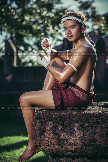The boxer sat on the stone, tied the tape around his hand, preparing to fight. Стоковое фото, агентство Ingram Publishing / Фотобанк Лори