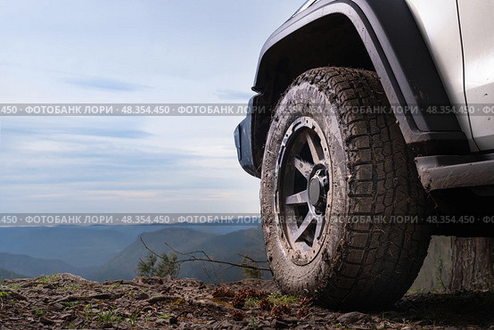 The concept of road trips and adventure tours on SUVs and cars in nature. A large wheel of an SUV on top of a mountain in close-up against the sky and space, the spirit of freedom. Стоковое фото, фотограф Владимир Разгуляев / Фотобанк Лори