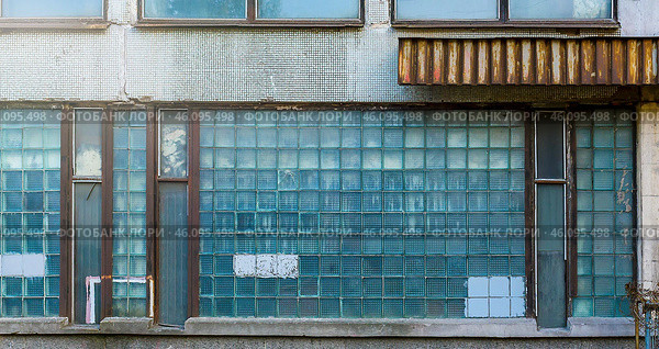 The facade of an old industrial building with windows of small square glasses. Uneven cracked surface. Perfect for background and grunge design. Стоковое фото, фотограф Андрей Степанов / Фотобанк Лори