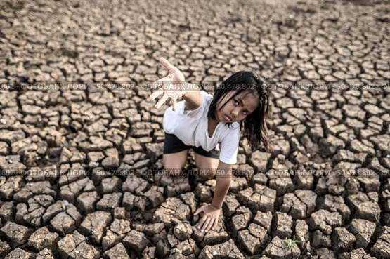 The girl sat elsewhere, hand to the sky to ask for rain on the dry ground,global warming. Стоковое фото, агентство Ingram Publishing / Фотобанк Лори