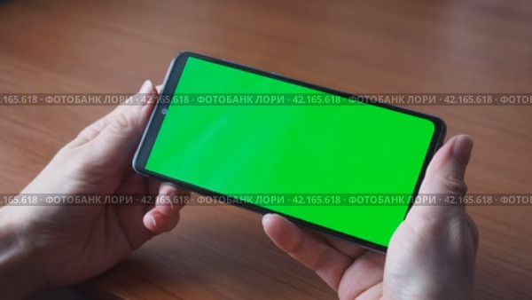 The green screen of a smartphone or chroma key. Women's hands hold the phone, click the touch screen. Close up Mock up. Стоковое видео, видеограф Глущенко Елена / Фотобанк Лори
