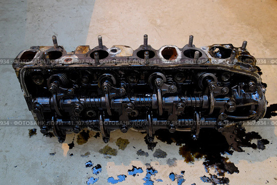 The head of the block of cylinders. The head of the block of cylinders removed from the engine for repair. Parts in engine oil. Car engine repair in the service. Стоковое фото, фотограф Леонид Еремейчук / Фотобанк Лори