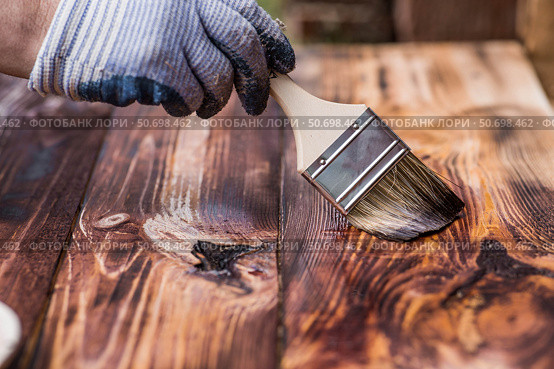 The procedure for protecting and coating wooden boards. A worker applies a protective wood stain with a brush. The process of restoring a hardwood flooring. Стоковое фото, фотограф Photojuli / Фотобанк Лори
