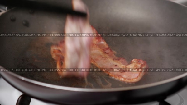The process of preparing breakfast with bacon. Flipping bacon pieces. Стоковое видео, видеограф Алексей Гекало / Фотобанк Лори
