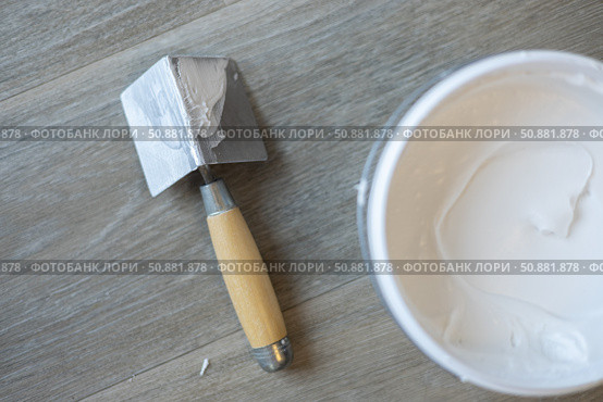 The spatula for the corners and the jar with putty. Laminated grey background. Repair concept, repair goods stores. Top down view. Copy space. Стоковое фото, фотограф Екатерина Топорова / Фотобанк Лори