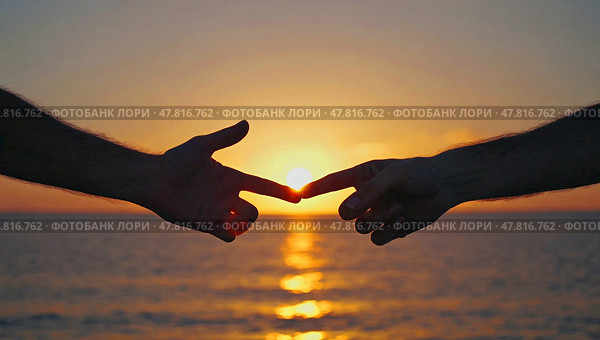 The touch of fingers against the sunset. The hands touch the other hand on the ocean shore in the rays of the setting sun. Стоковое AI-изображение, AI-художник Антон Слабоспицкий / Фотобанк Лори