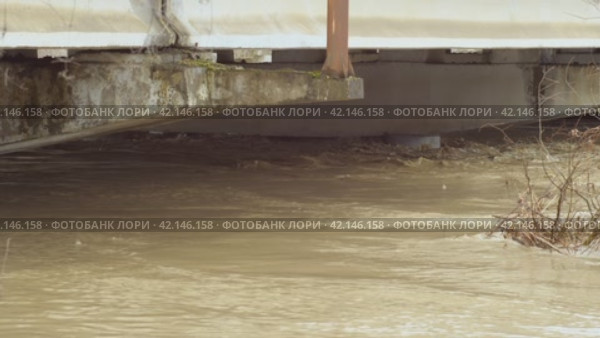 The water has risen to top of bridge pier. Thick, large concrete piers under water. A flowing river after heavy rain. An incredibly fast river. The flow of a dangerous wild river. Natural disasters. Стоковое видео, видеограф Воловодов Владимир / Фотобанк Лори