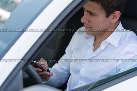 The young man behind the wheel driving car and calling phone. Стоковое фото, фотограф Kirill Kedrinskiy / Ingram Publishing / Фотобанк Лори