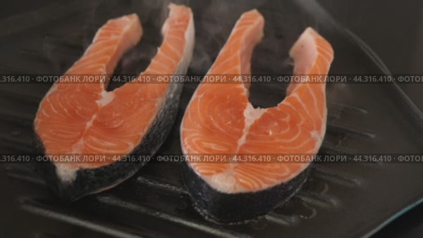 There are two pieces of broiled salmon steaks in square black frying pan. Стоковое видео, видеограф Яков Филимонов / Фотобанк Лори