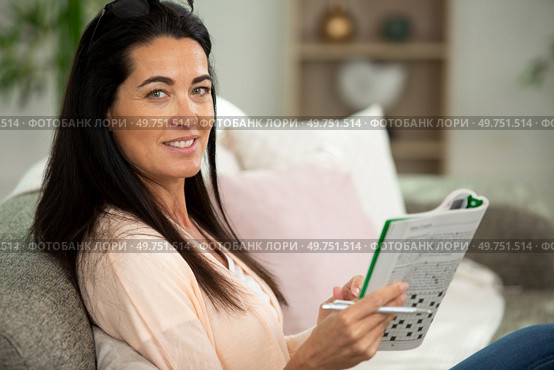 thoughtful woman doing a cryptic crossword puzzle. Стоковое фото, агентство Ingram Publishing / Фотобанк Лори