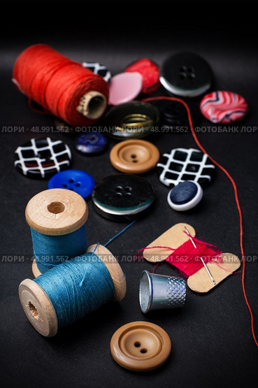 thread and buttons for sewing master on black background.Selective focus. working tool dressmaker. Стоковое фото, агентство Ingram Publishing / Фотобанк Лори