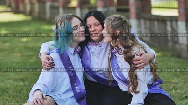 Three happy graduates hugging and celebrating their last school day, wearing purple sashes and bow ties. Стоковое фото, фотограф Mikhail Davidovich / Фотобанк Лори