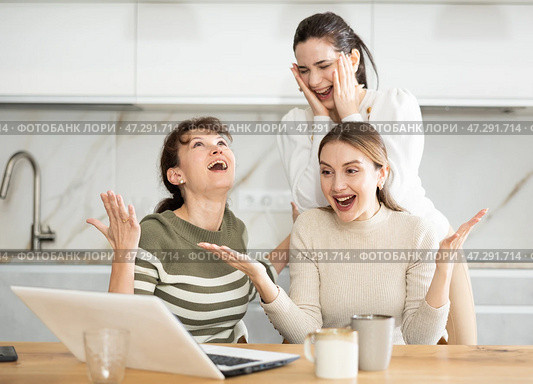 Three happy middle-aged woman expressing joy for winning in the kitchen. Стоковое фото, фотограф Яков Филимонов / Фотобанк Лори