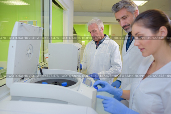 Three lab technicians using machinery. Стоковое фото, агентство Ingram Publishing / Фотобанк Лори