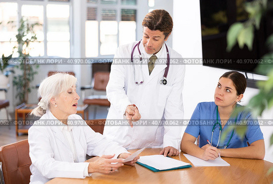 three positive doctors are sitting at table animatedly and actively discussing current work. Стоковое фото, фотограф Яков Филимонов / Фотобанк Лори