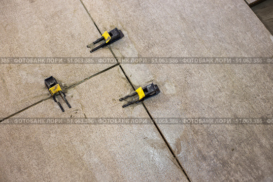 Tile leveling clips are installed between laid floor tiles, ensuring a uniform distance between them and a level surface. Стоковое фото, фотограф Коханова Наталья / Фотобанк Лори